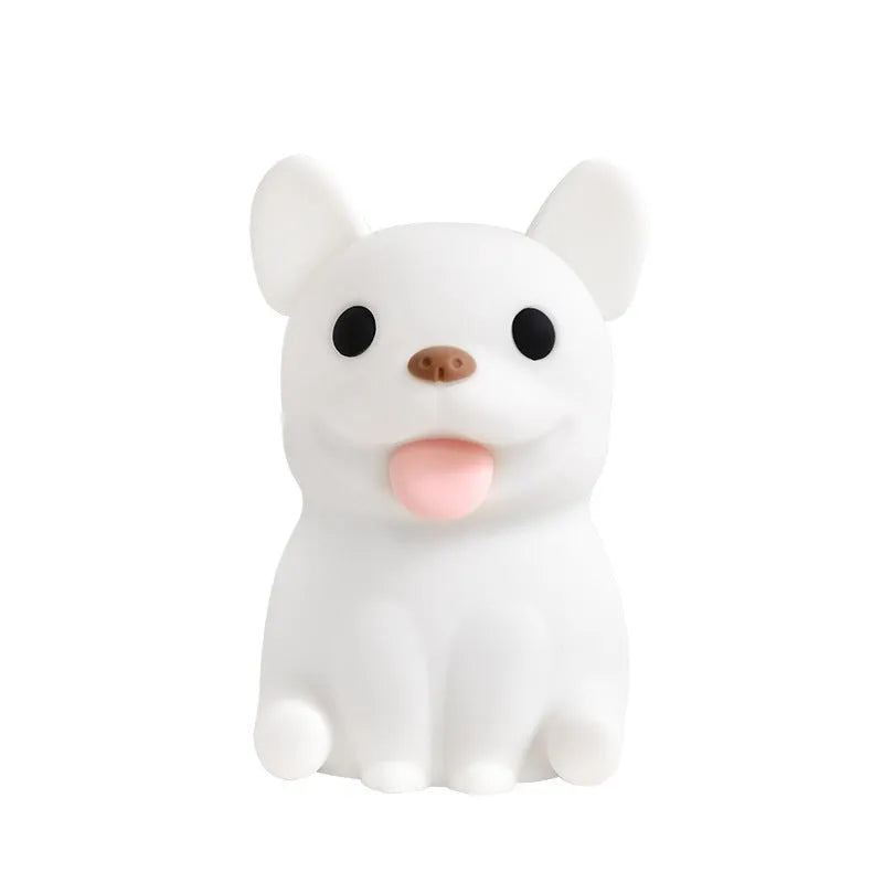 Soft silicone animal or cartoon-themed USB night light with dimming function on a bedside table.
