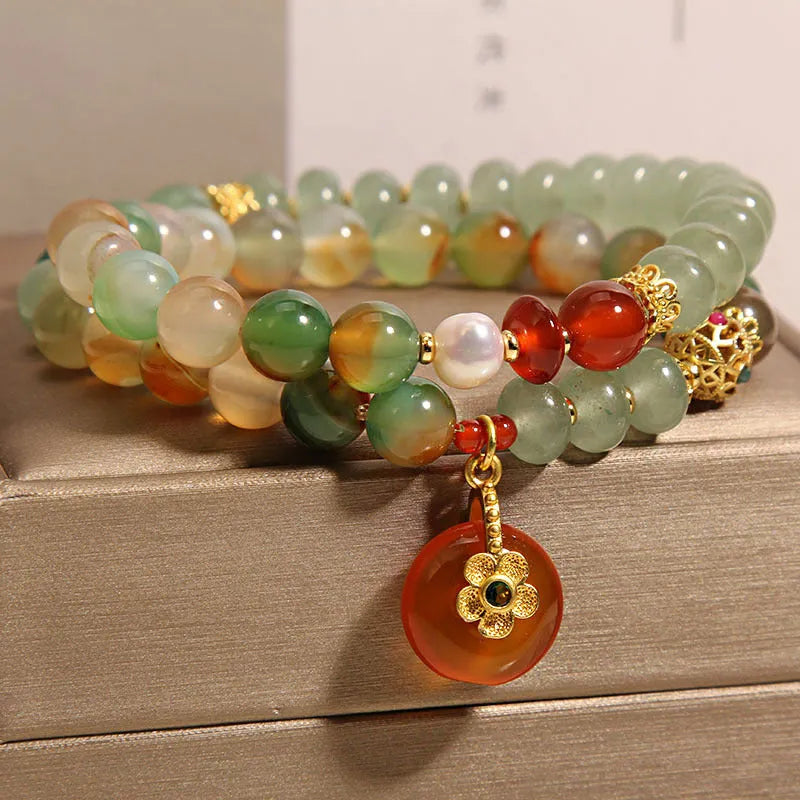Women's peacock green agate double ring bracelet with safety buckle and rhinestones on a wrist.