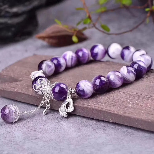 Women's amethyst bracelet with 10mm round purple beads on a wrist.