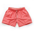 Men's polyester surf shorts in multiple colours on a beach background, showing straight leg design.