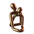 Modern minimalist loving couple resin statue in milky white or gold finish on wooden surface