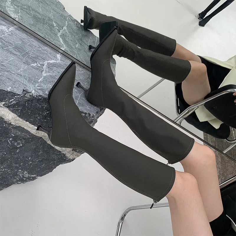 Women's pointed toe knee-high boots in black with a stiletto heel and a visible back zipper closure.