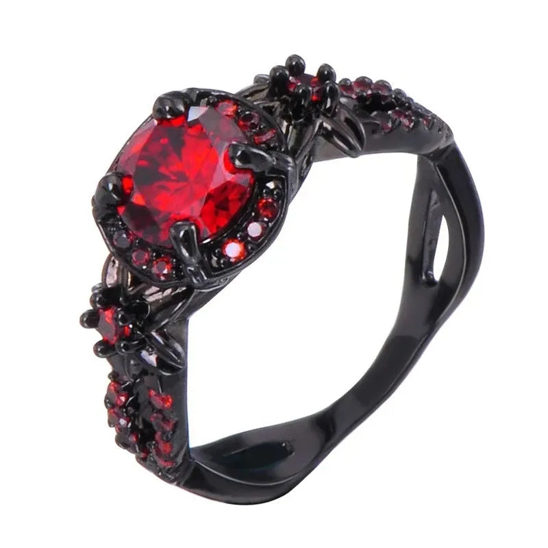 Black gold plated copper ring with round red zircon stone and wave-shaped band on finger