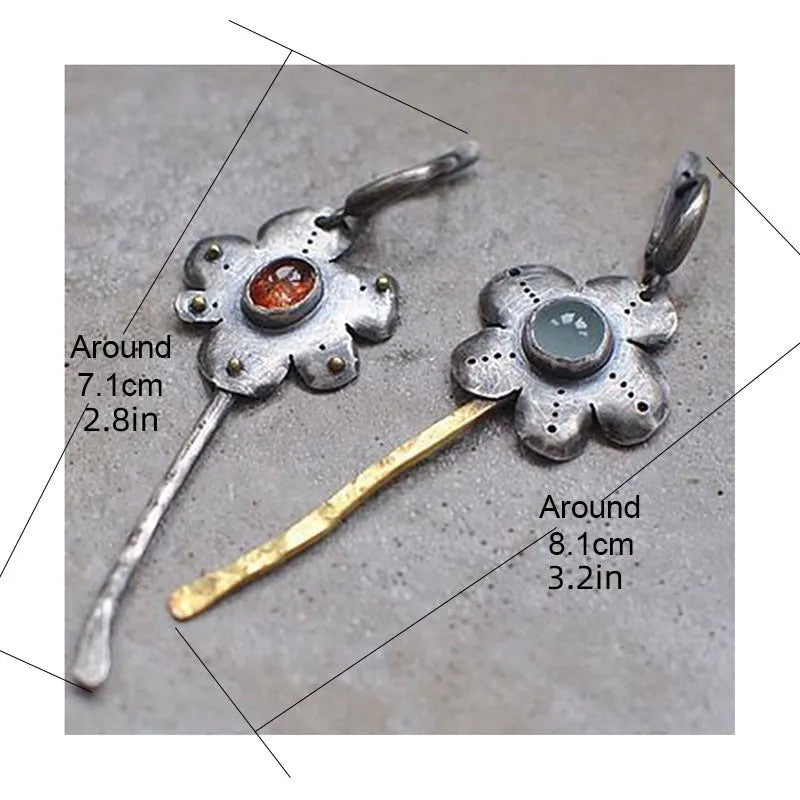 A pair of long, geometric flower-shaped drop earrings with an asymmetric two-tone metallic finish.