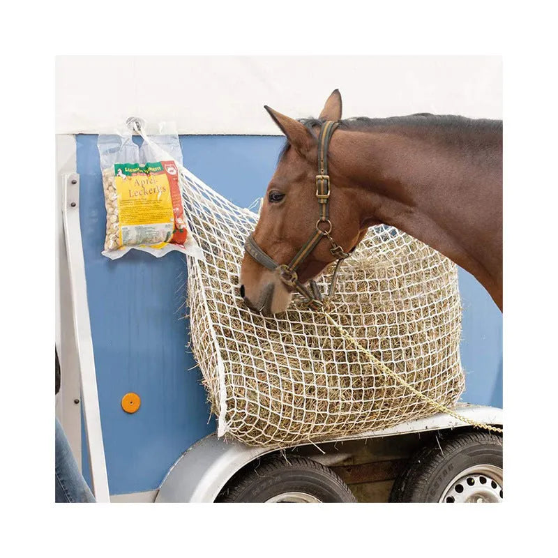 Black woven grid horse feeding bag hanging, filled with hay.