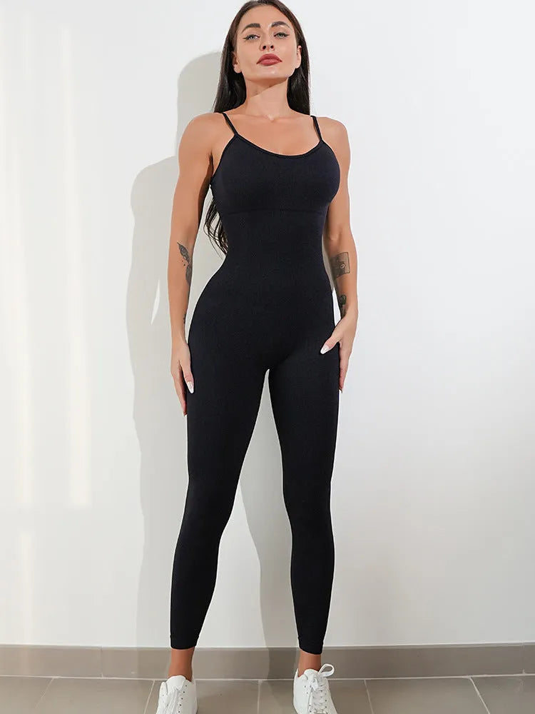 A woman wearing a black sleeveless, backless unitard jumpsuit with thin spaghetti straps.