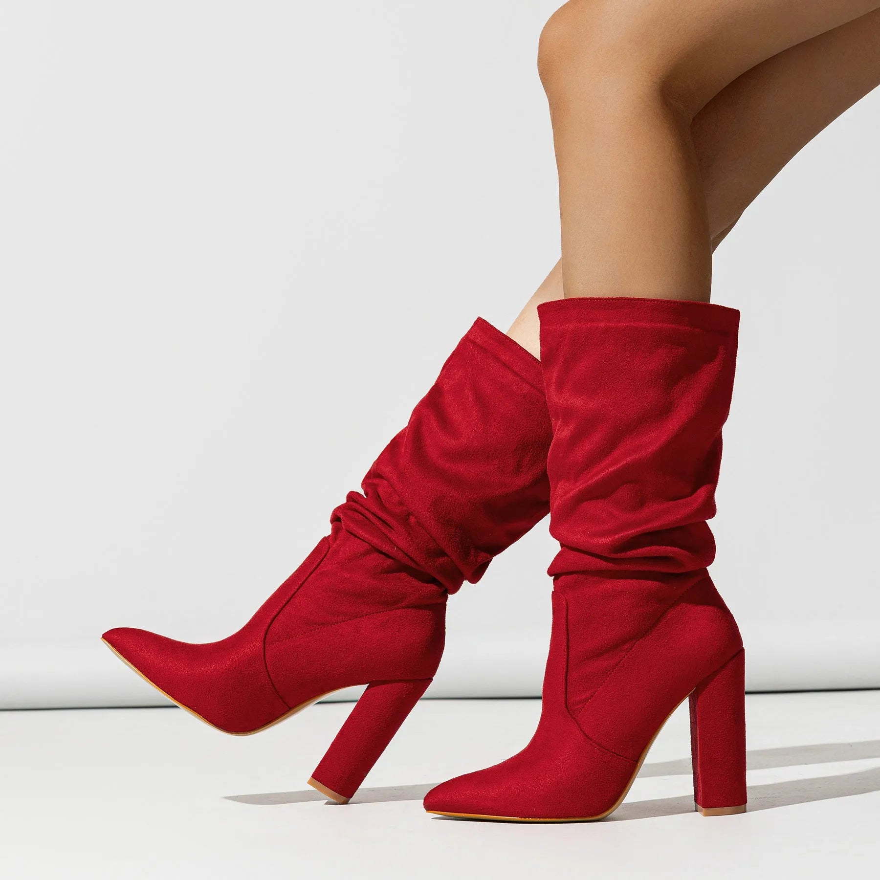Women's black suede pointed-toe ankle boots with a chunky high heel, shown on a mid-calf.