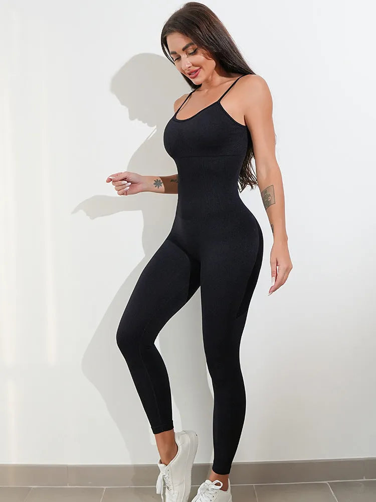 A woman wearing a black sleeveless, backless unitard jumpsuit with thin spaghetti straps.
