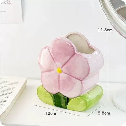 Ceramic pen holder box with floral decoration on a desk, holding pens.