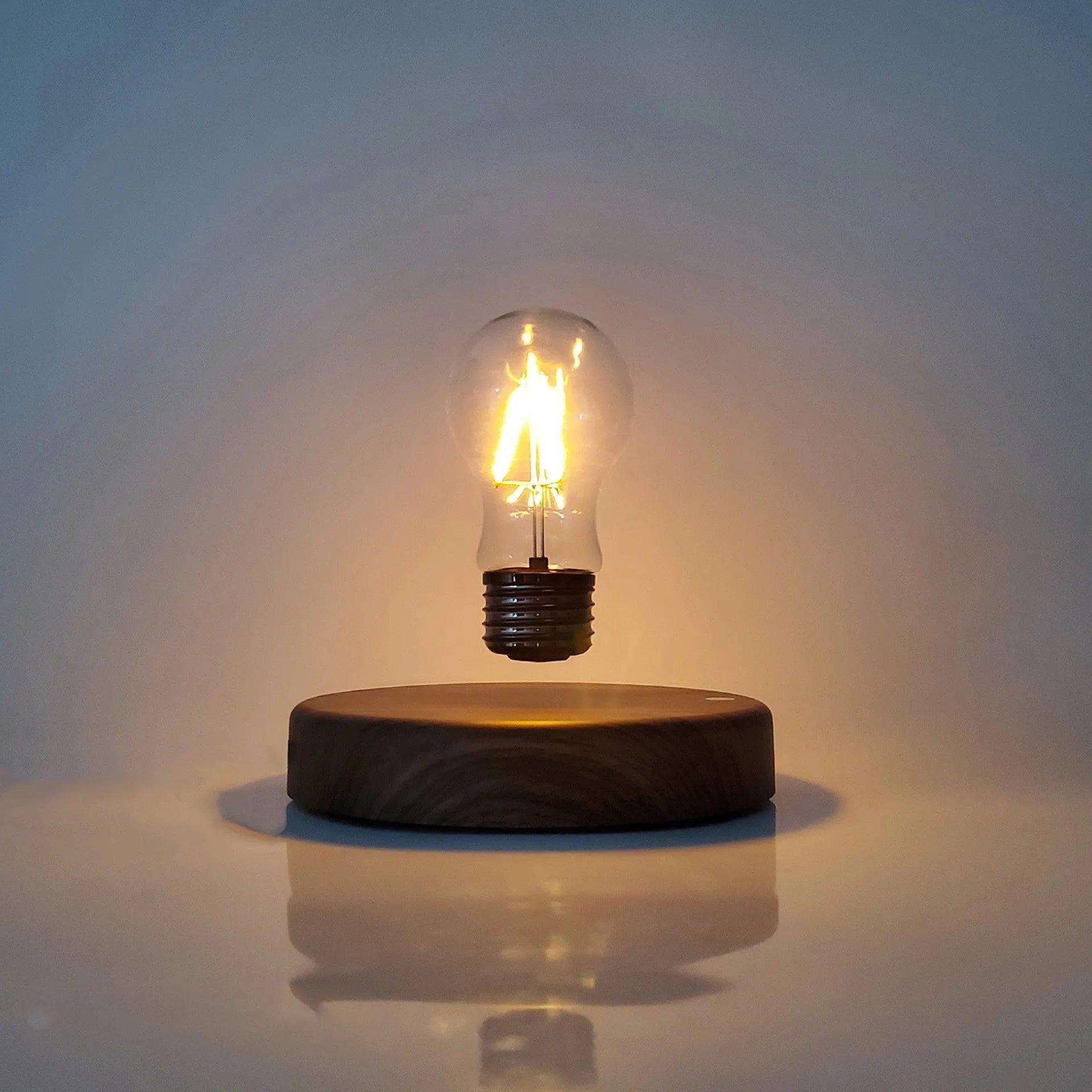Magnetic levitation desk lamp with floating bulb on a solid wood colour base.