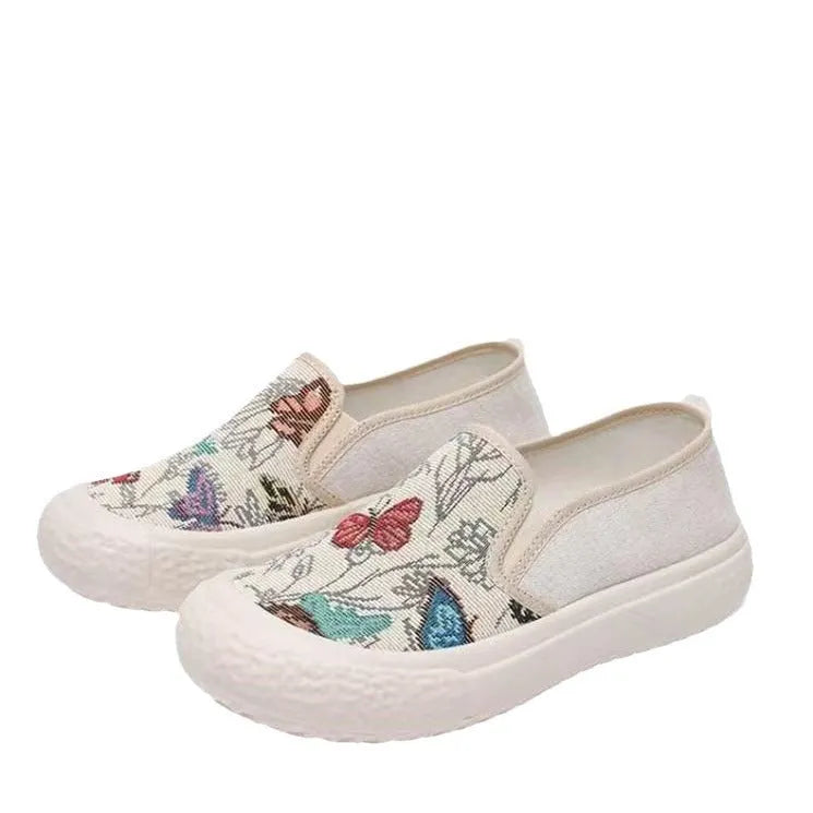 Women's black and white canvas slip-on shoes with round toe and decorative stitching.