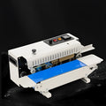 Mini benchtop heat sealing machine with steel jaw and integrated date print function on a work surface.