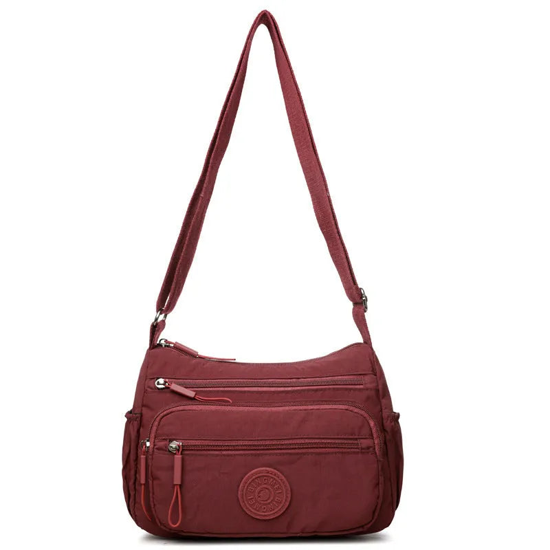 Water-repellent nylon crossbody bag in grey, showing front 3D pocket and single strap.