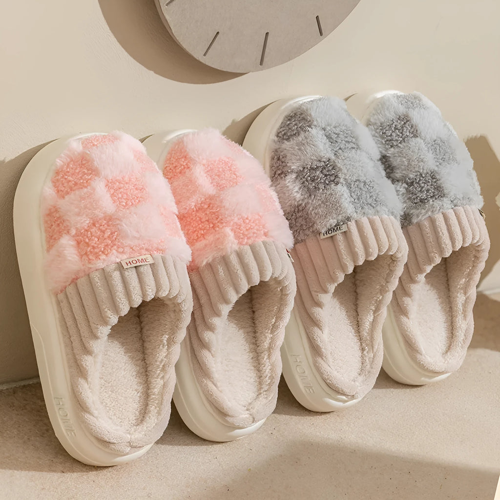 Plaid pattern women's plush indoor slippers in grey with a round toe and flat heel on a non-slip sole.