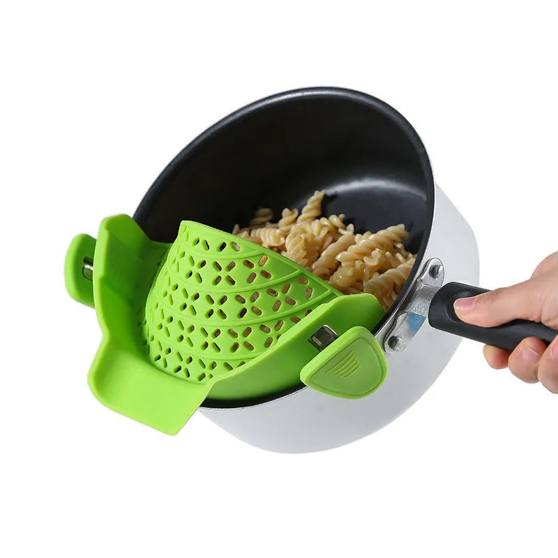Green silicone pot drain stopper with stainless steel insert on a kitchen countertop.
