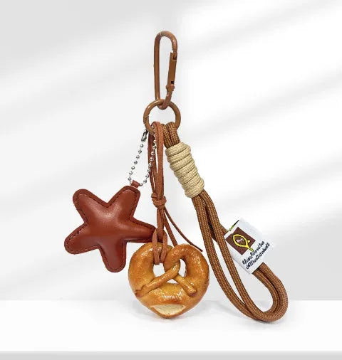 Handmade soda bread handbag charm pendant with cartoon croissant design and brown strap