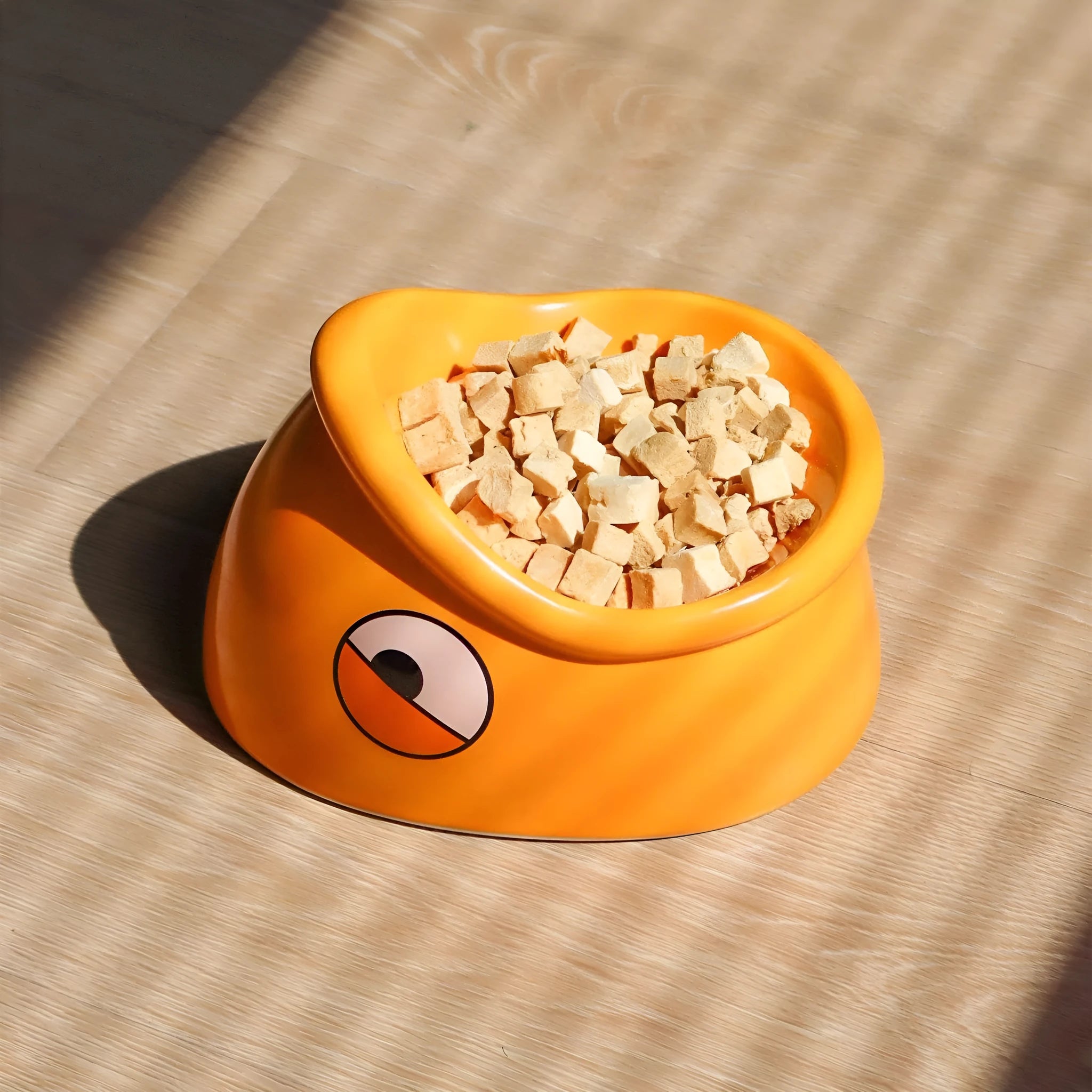 Orange ceramic pet food bowl with fish head pattern, 196x121x149mm, on floor
