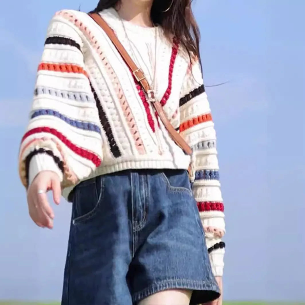 Retro rainbow striped pullover sweater with batwing sleeves on a hanger.