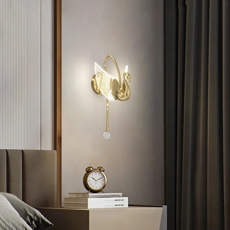 Gold minimalist swan-shaped wall lamp with an acrylic shade mounted on a wall.