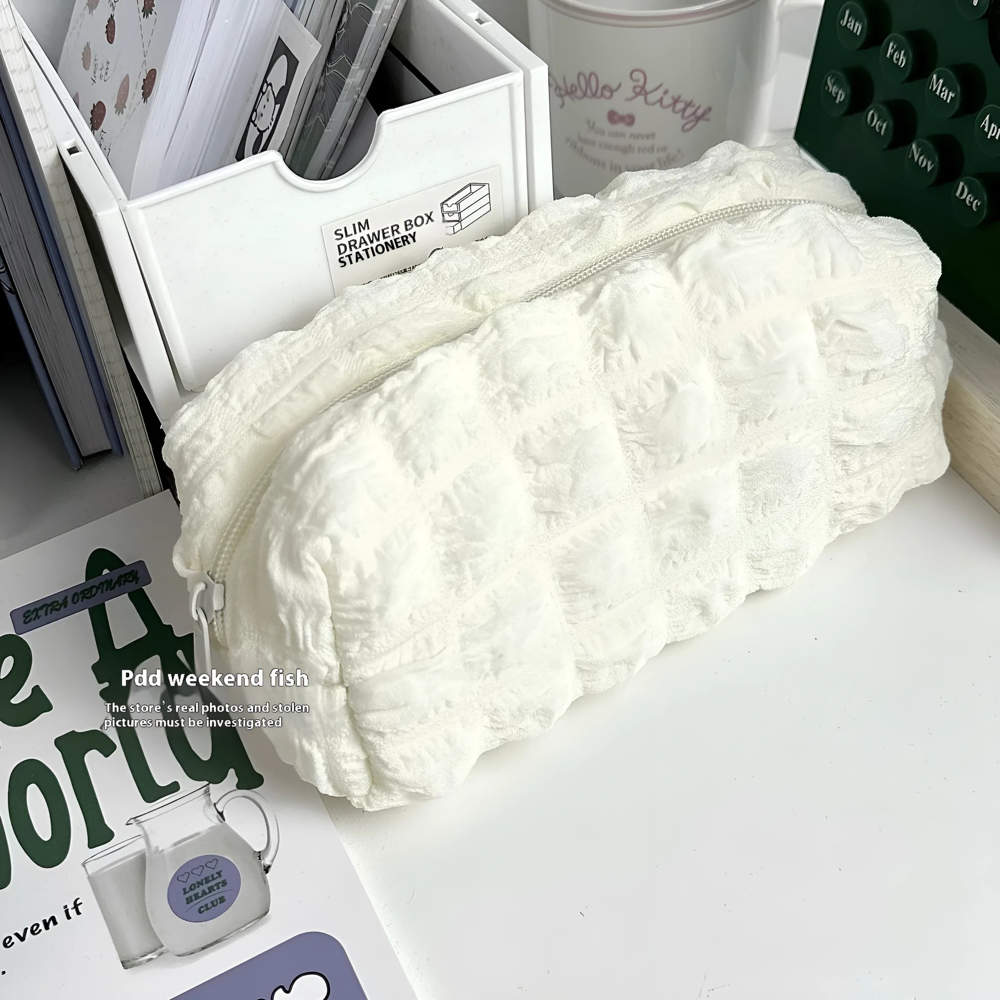 Beige and black fabric cream puff style pencil case made from polyester.
