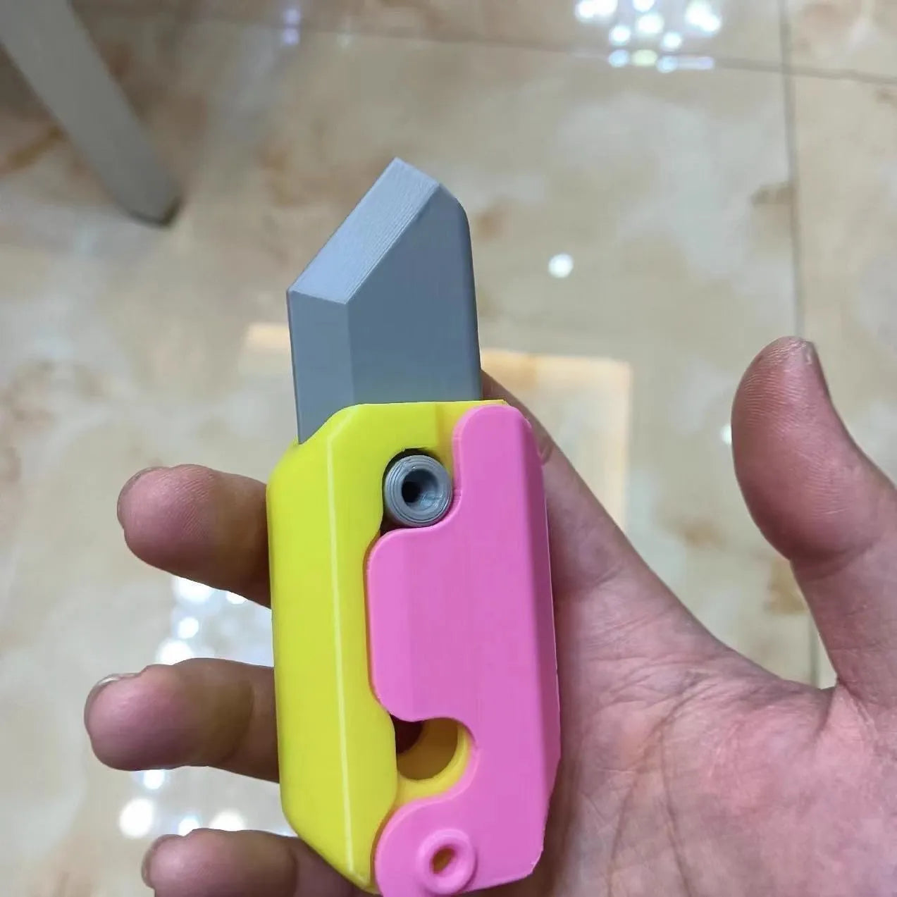 3D printed plastic gravity carrot knife fidget toy in orange, purple, and green colours.