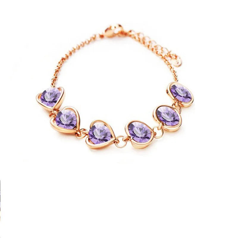 Heart shaped alloy bracelet with crystal inlay, shown in a choice of seven colours including sapphire blue and light purple.