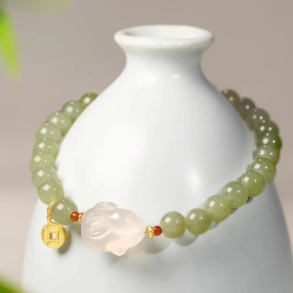 Close-up of a women's handmade bracelet with a detailed jade rabbit charm in a gift box.