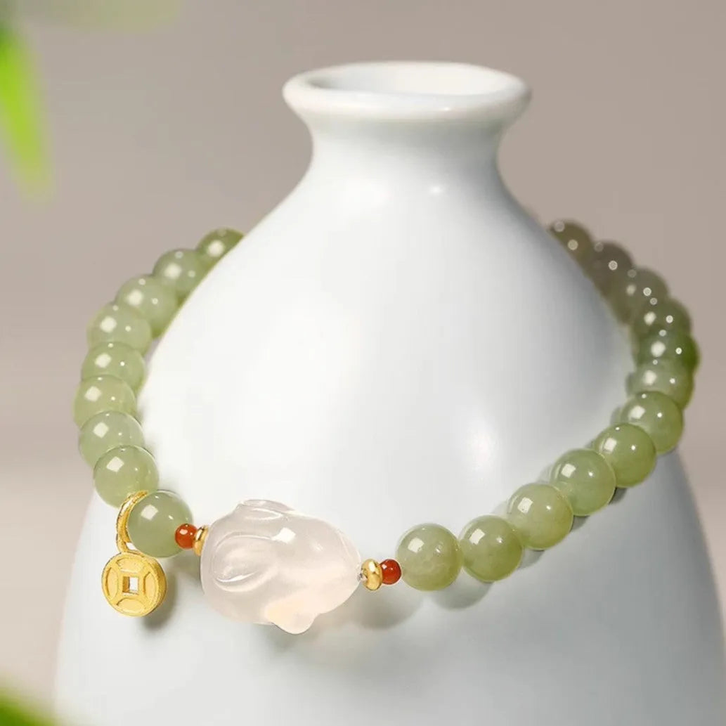 Close-up of a women's handmade bracelet with a detailed jade rabbit charm in a gift box.