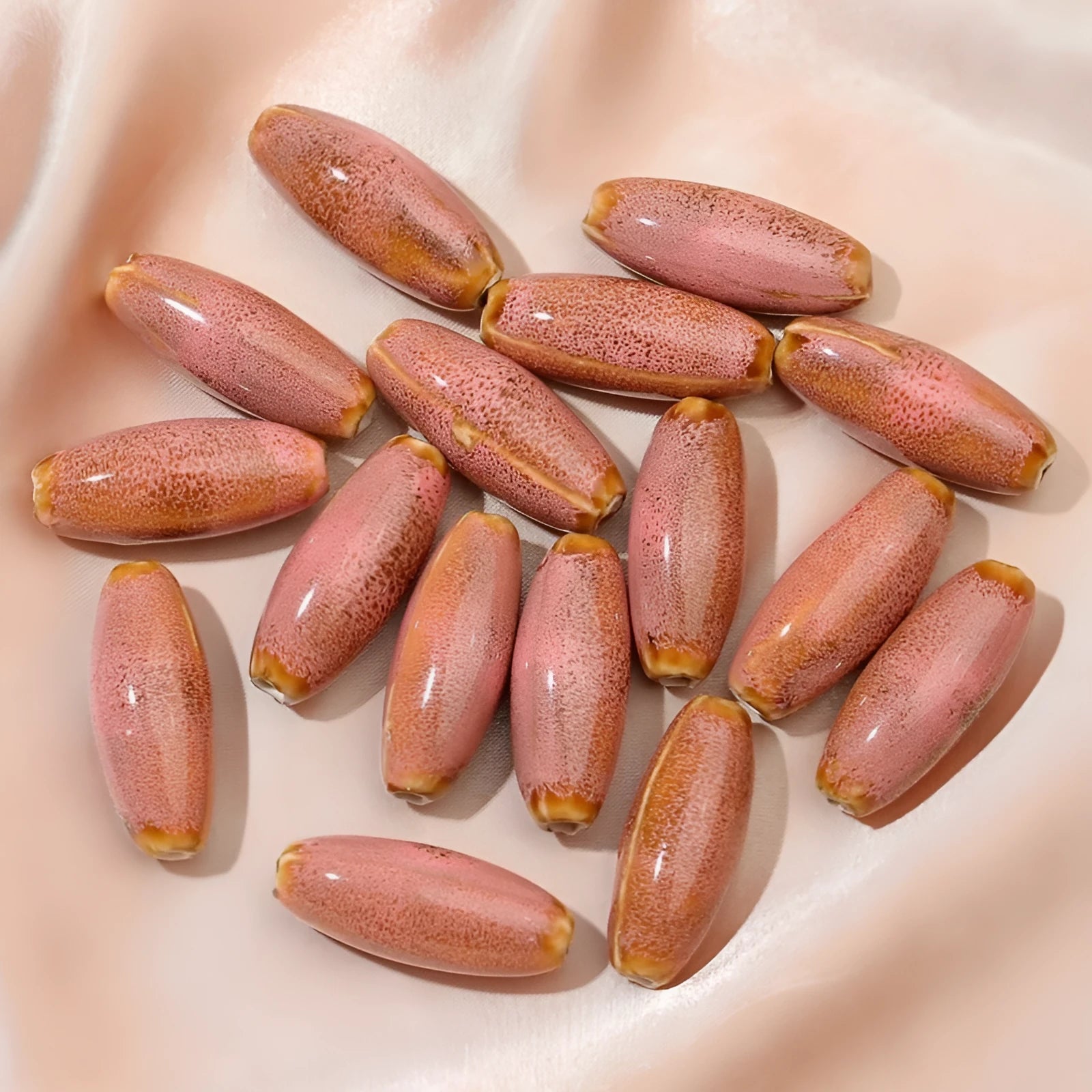 Assortment of ceramic bullet beads in pink, yellow, blue, red, coffee, green, orange, and mixed flower glaze colours.