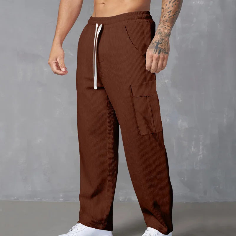 Men's loose-fitting corduroy cargo trousers in a brick red colour with a wide-leg silhouette.
