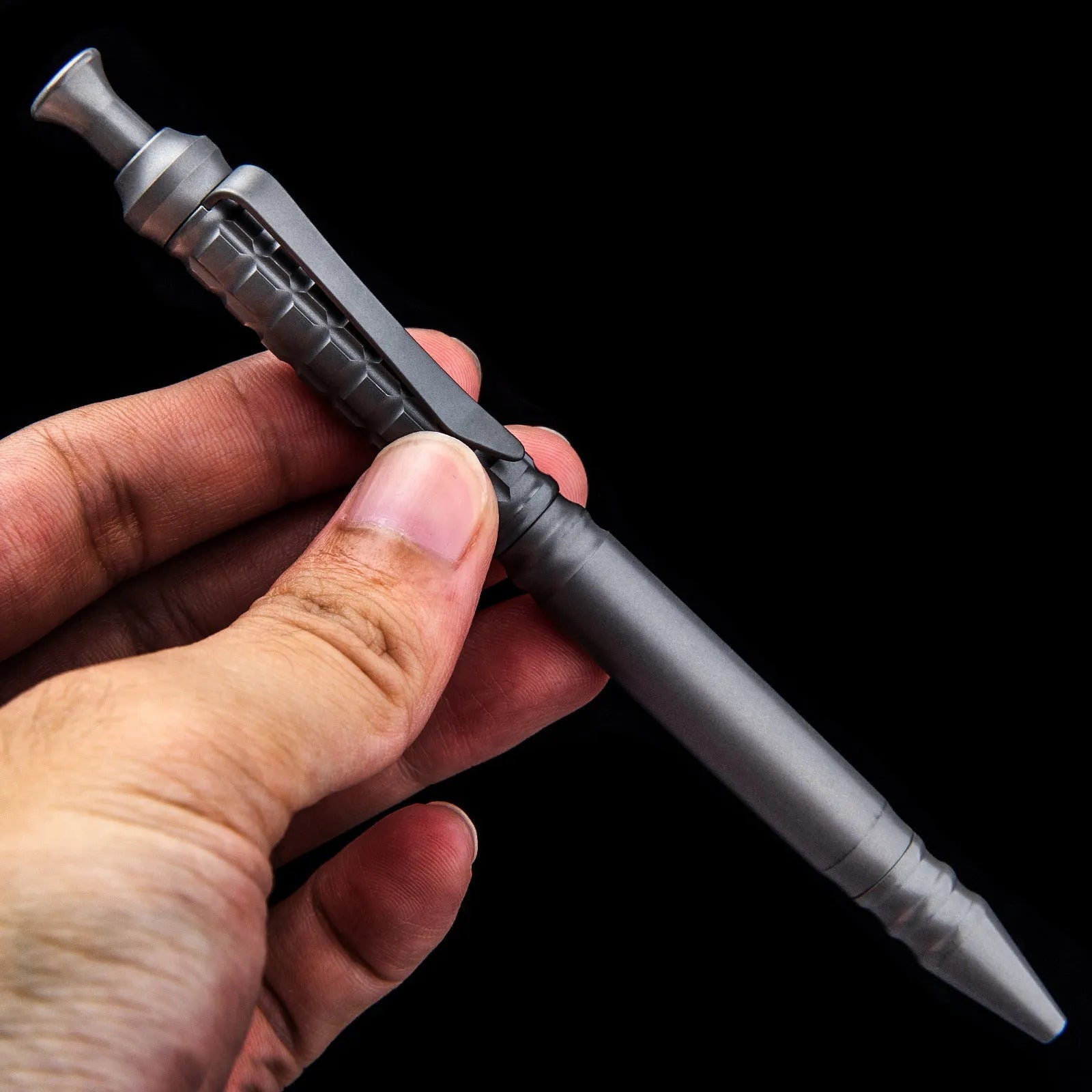 Gunmetal grey titanium alloy tactical pen with push-action mechanism on a gift box.