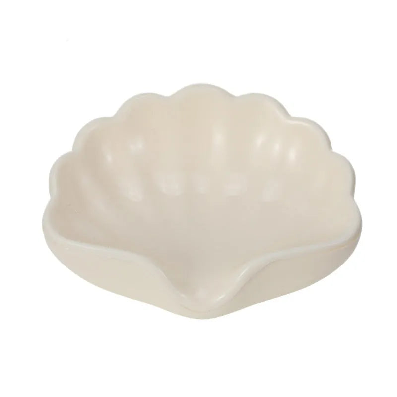 White plastic shell-shaped soap dish for bathroom vanity storage.