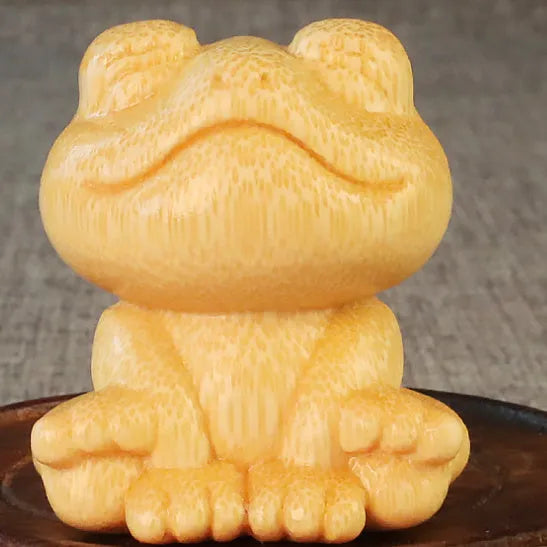 Solid bamboo carving of a smiling cartoon frog ornament, 5cm tall.