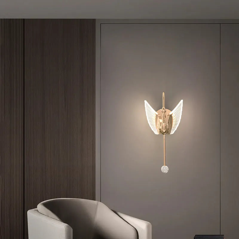 Gold minimalist swan-shaped wall lamp with an acrylic shade mounted on a wall.