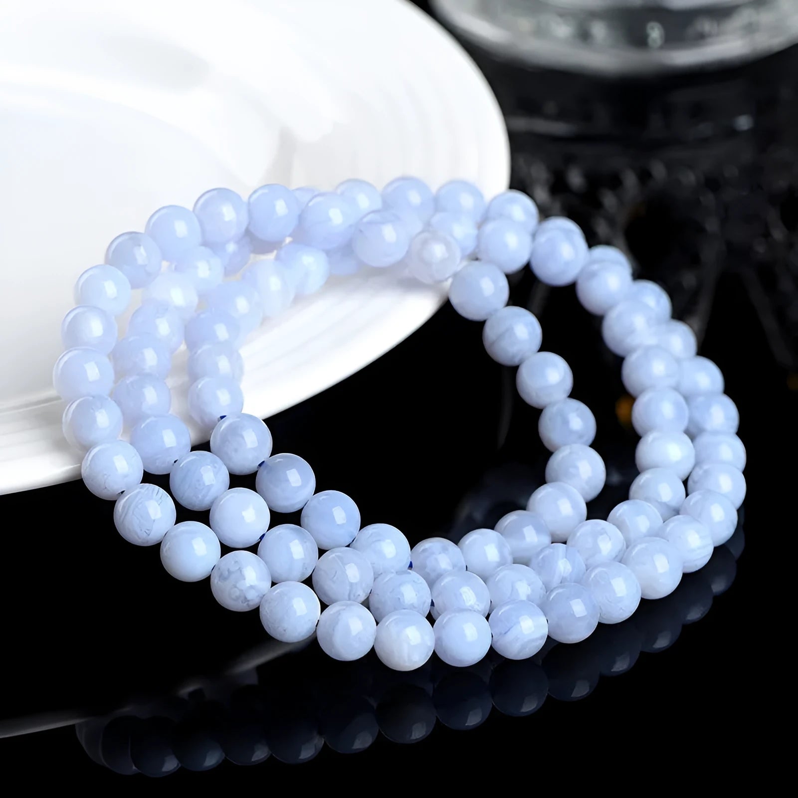 Blue agate bead bracelet with striped patterns and a Ruyi charm on a white background.