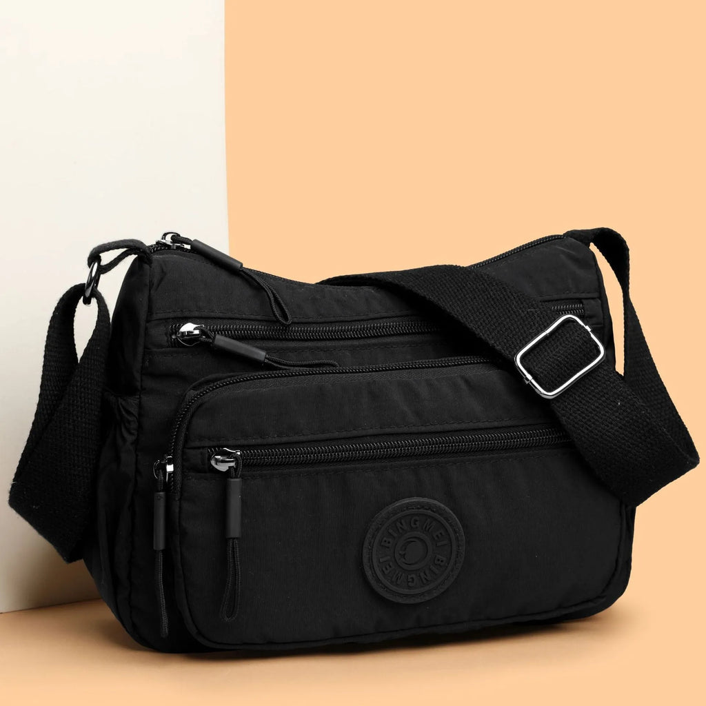 Soft water-repellent nylon crossbody bag with a three-dimensional front pocket and adjustable strap.