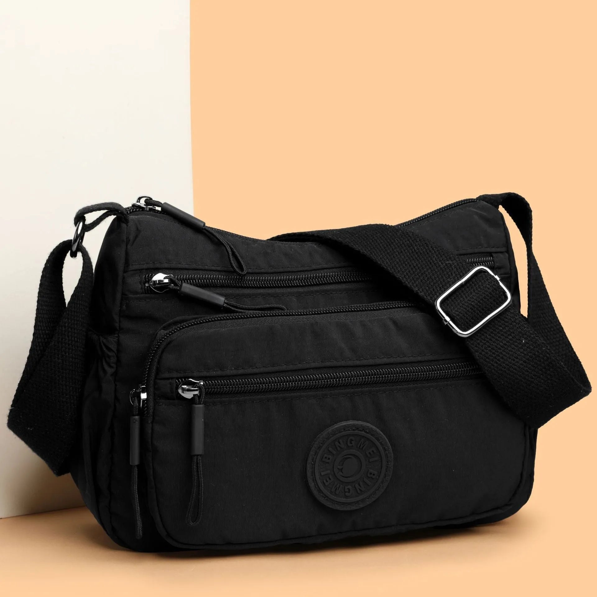 Soft water-repellent nylon crossbody bag with a three-dimensional front pocket and adjustable strap.