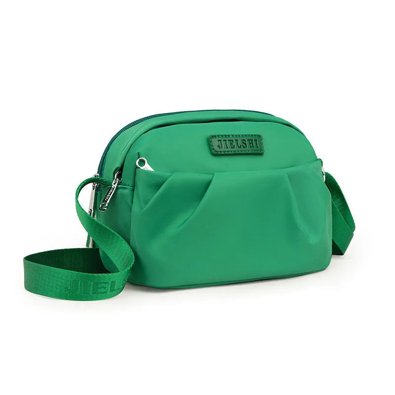 Pleated Oxford cloth horizontal messenger bag in cangling green, showing cross-body strap and external pocket.