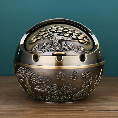 Alloy decorative ashtray in bronze with ornate peacock motif and cigarette extinguishing slot.