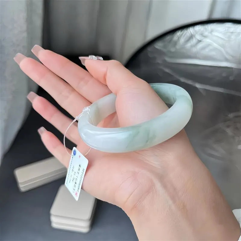 Clear ice-like jade bracelet with floating floral design and zodiac motif on a wrist.