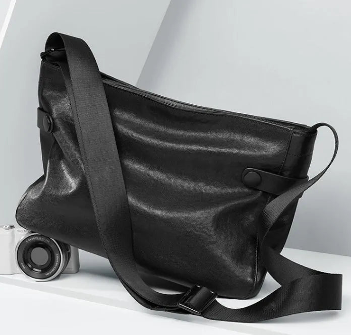 Men's black genuine leather and cowhide crossbody messenger bag with waterproof function and patchwork detail.