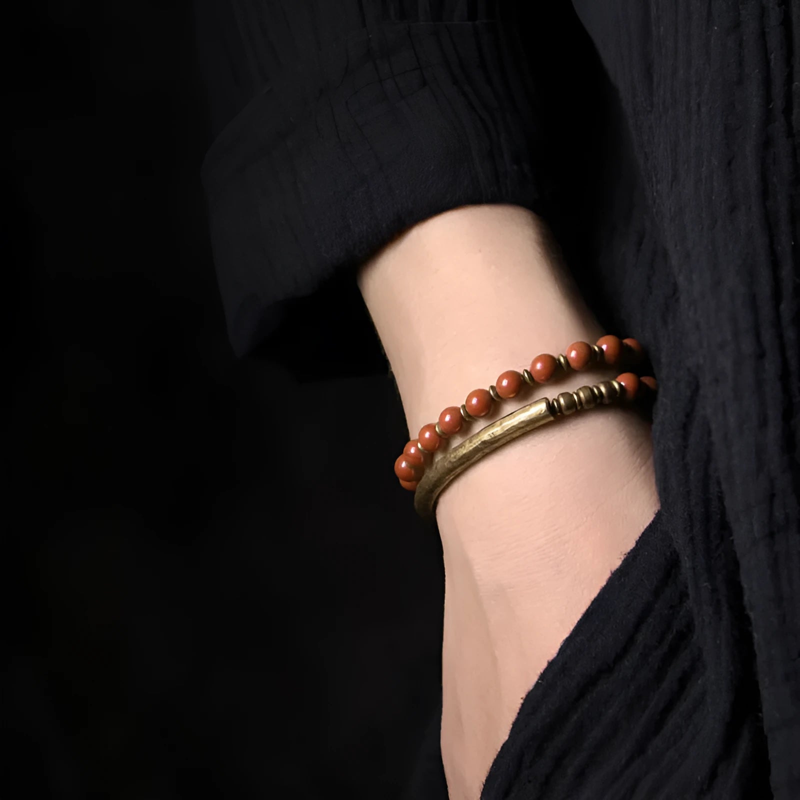 Layered ethnic bracelet with gemstone beads and brass details on a wrist, showing adjustable unisex design.