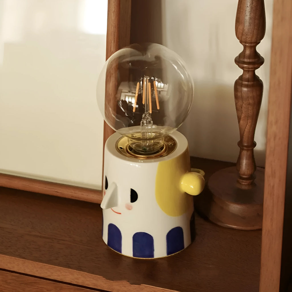 Handmade ceramic bedside lamp with a white ball headlight on a wooden table.