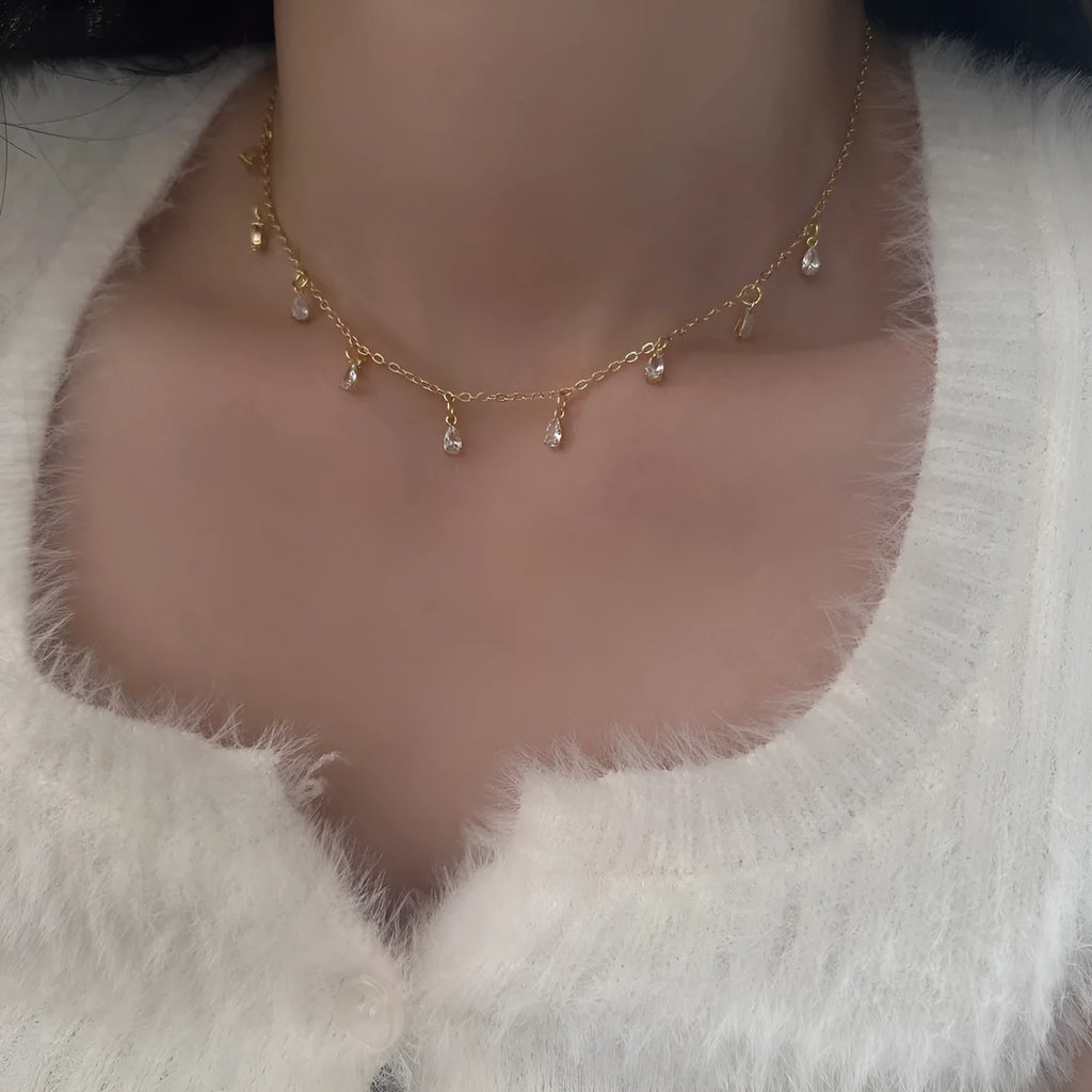 A zircon jewellery set comprising a geometric pendant necklace, stud earrings, and an anklet on a white background.