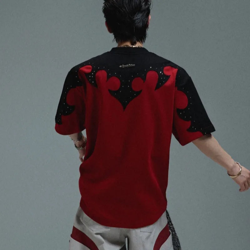 Close-up of a men's grey t-shirt with raised burnt flower embroidery and sparkling rhinestone details on the chest.