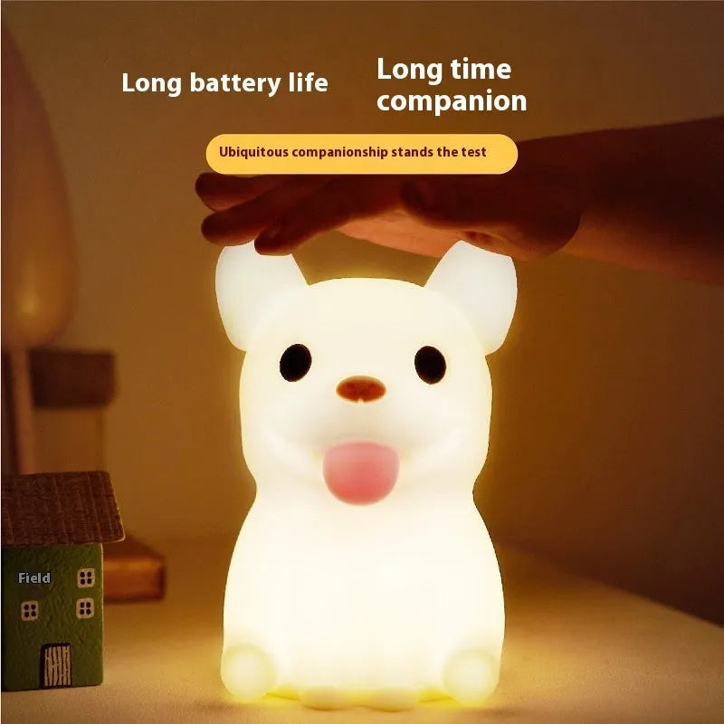 Soft silicone animal or cartoon-themed USB night light with dimming function on a bedside table.