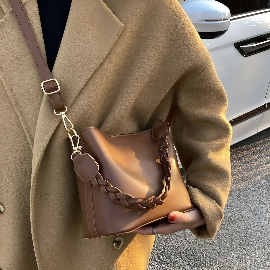 Khaki woven crossbody bucket bag with a buckle, shown on a model for scale