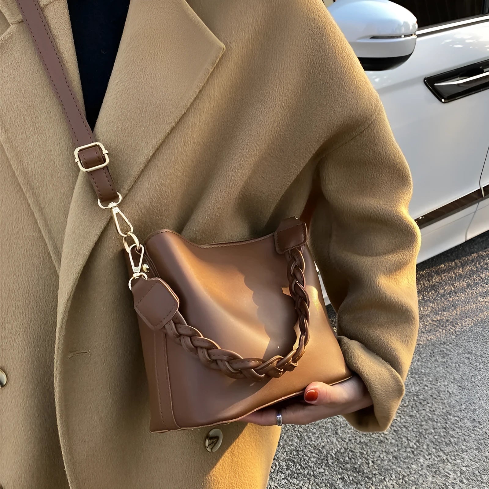 Khaki woven crossbody bucket bag with a buckle, shown on a model for scale