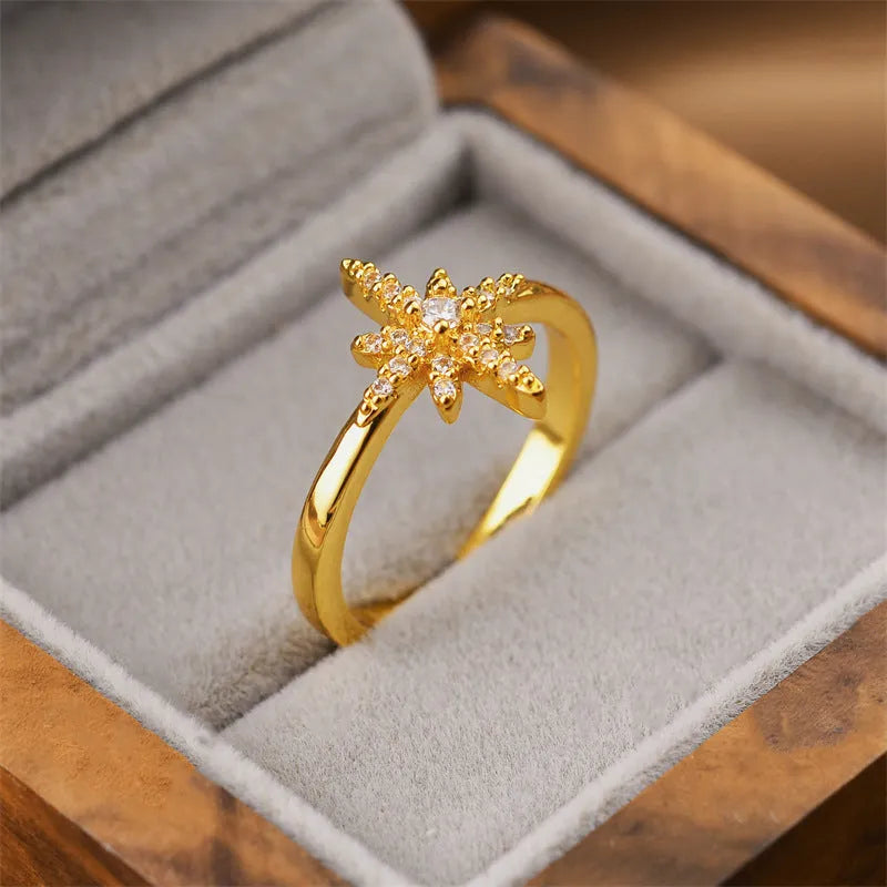 Geometric open ring in gold colour on a plain background.