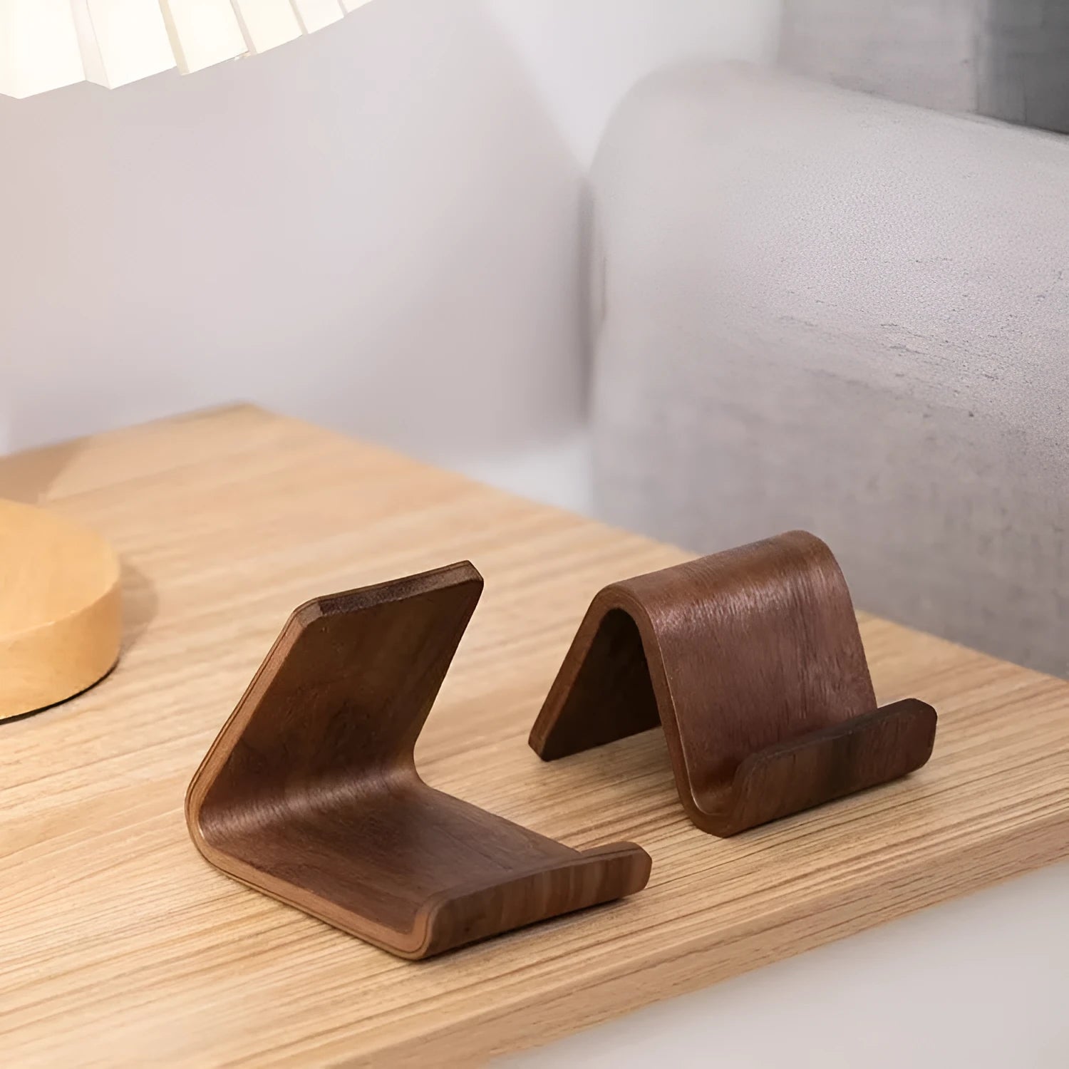 Walnut wood mobile phone bracket on a desk holding a smartphone upright for handsfree viewing